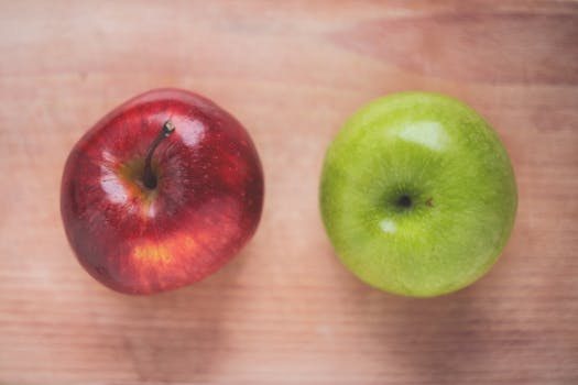 Close-up of a red and a green apple on a wooden table, ideal for healthy eating themes.