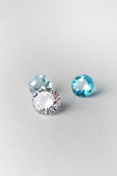 Close-up of sparkling blue and white gemstones on a smooth white surface, showcasing brilliance.
