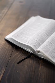 An open Bible resting on a wooden table, captured with natural lighting for a serene atmosphere.