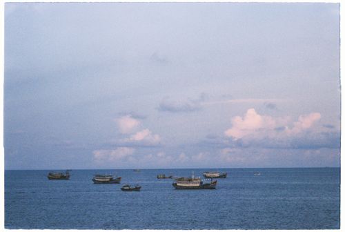 Free A serene seascape with traditional boats on calm waters under a pastel sky. Stock Photo