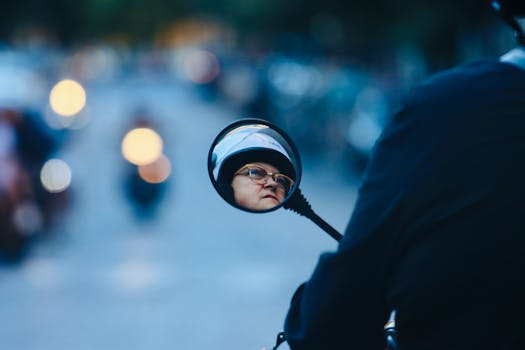 A woman wearing a helmet is reflected in a motorcycle mirror on a busy street in Naples, Italy.