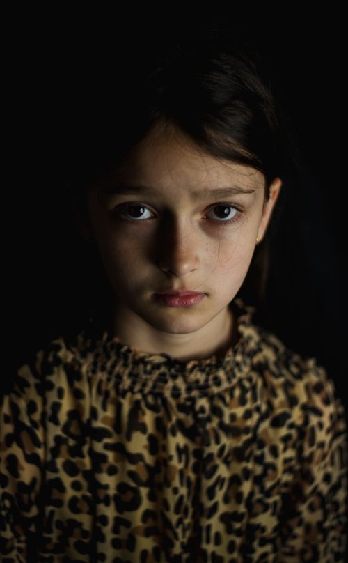 Free Close-up portrait of a young girl with a serious expression, wearing leopard print. Stock Photo