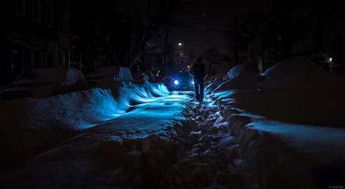 Person Walking on Footpath in Snow at Night
