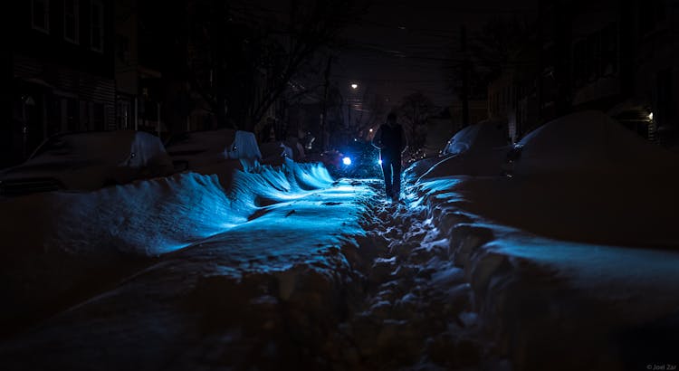 Person Walking On Footpath In Snow At Night