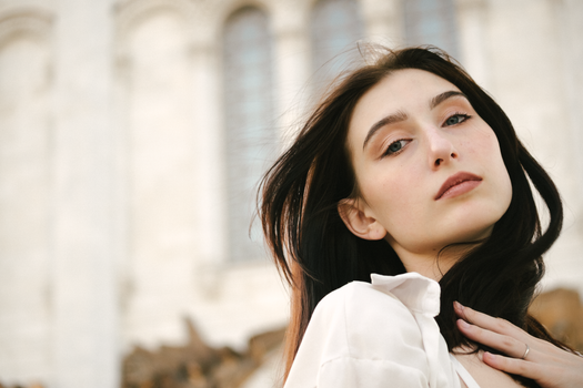Close-up portrait of a woman with long brown hair in a soft, elegant setting.