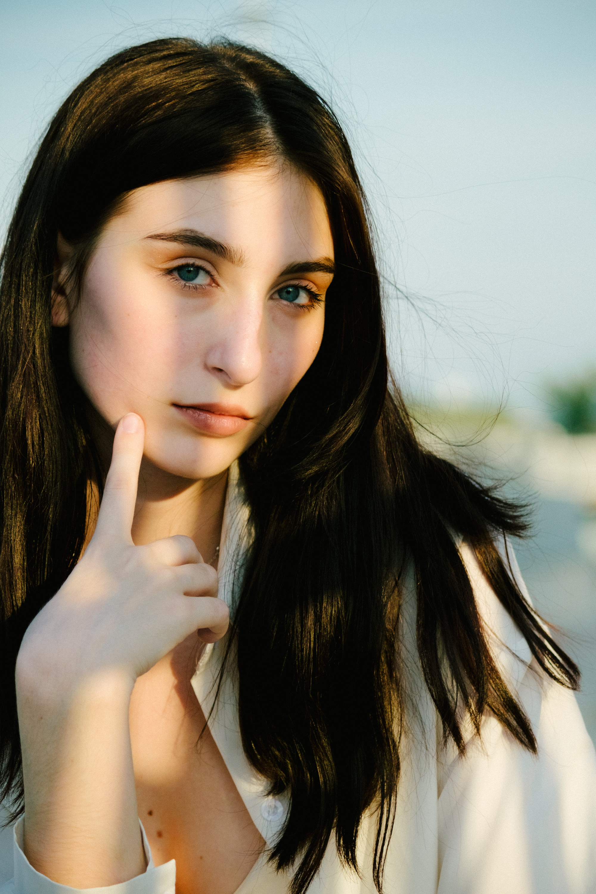 Portrait of a woman with long hair in natural light, exuding a serene and thoughtful ambiance.