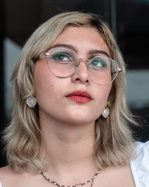 Free Young woman with glasses and blonde hair looking upwards. Stylish and modern. Stock Photo