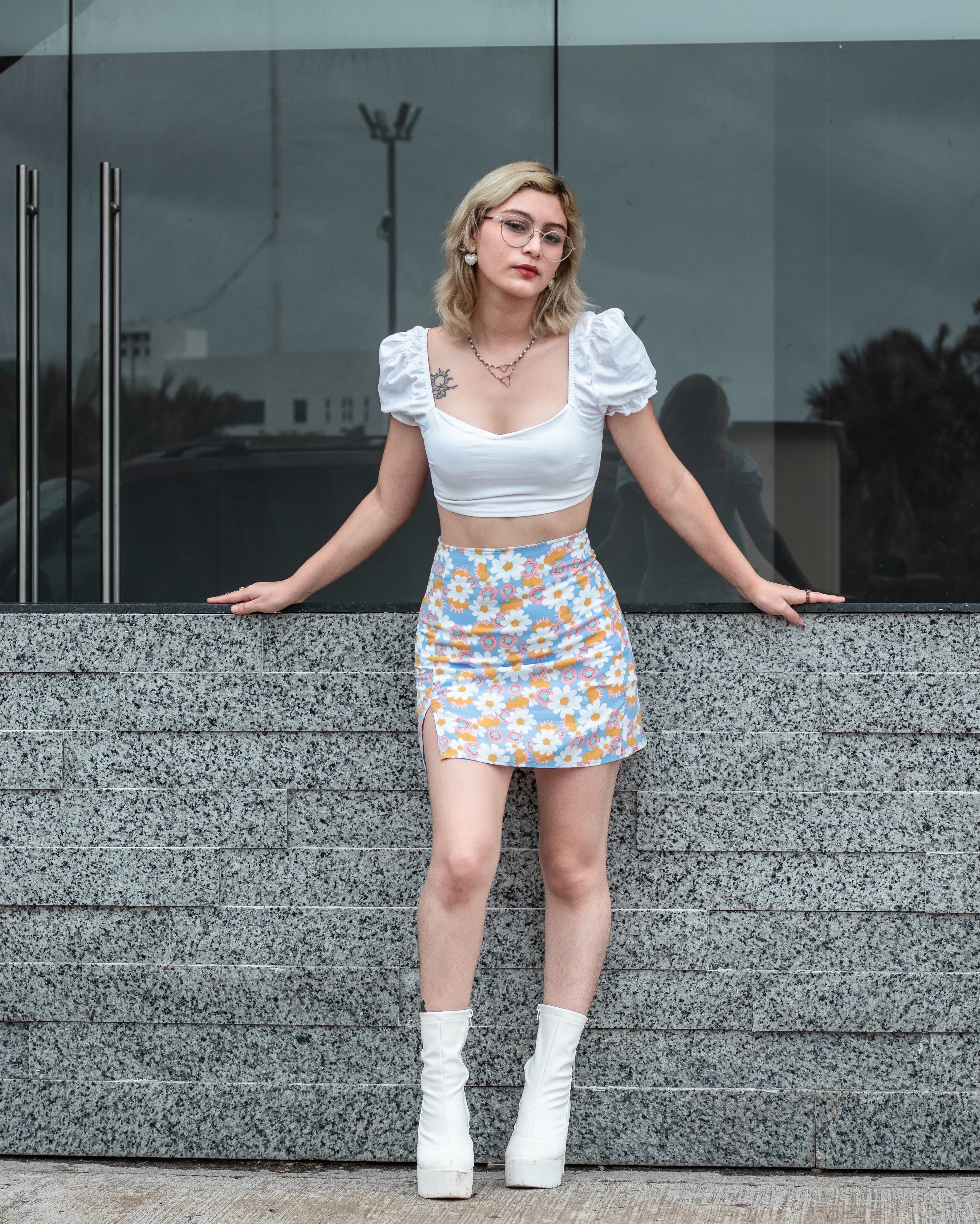 Mulher estilosa posando em uma saia floral contra um fundo moderno.