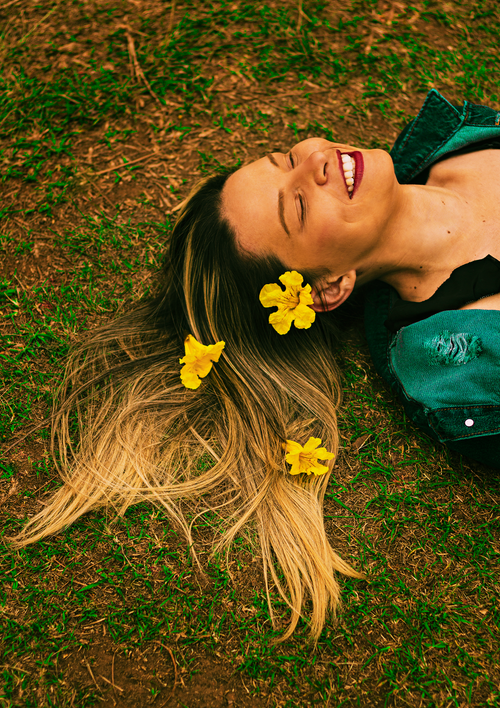 Free Smiling woman lying on grass with yellow flowers in her hair, eyes closed. Stock Photo