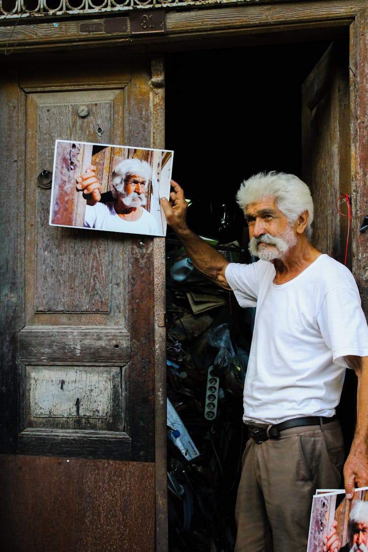 Old Man Posing With Photo Near Wooden Doors