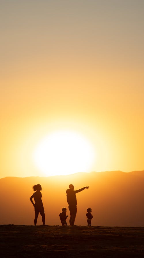 Silhouette of People Standing on Top of Mountain during Sunset