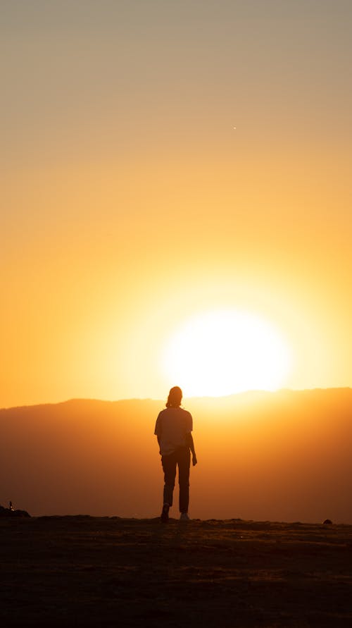 Silhouette of a Person Standing on Hill during Sunset