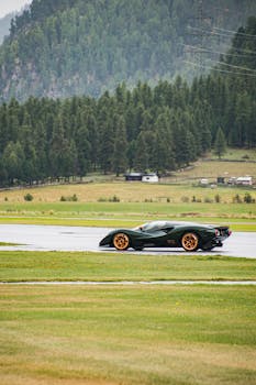 High-performance sports car on a lush green track in scenic Switzerland.