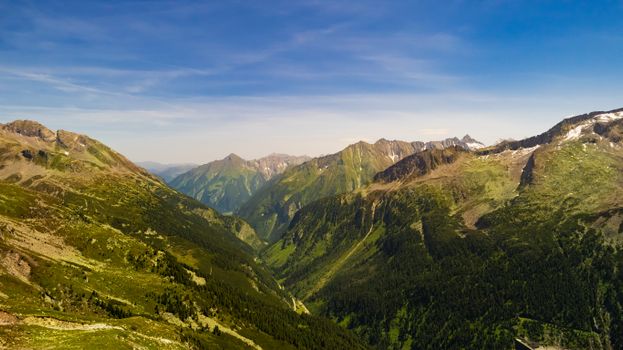 Stunning aerial view of lush green mountain range under a clear blue sky.
