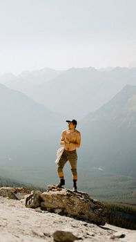 Shirtless man standing on rock with breathtaking view of Banff mountains, symbolizing adventure.