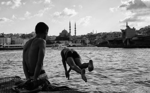 Free Men diving into the Bosphorus with Istanbul skyline, showcasing vibrant culture. Stock Photo