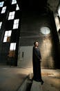 一个穿着黑色连衣裙的人站在废弃的工业大楼里，显得很怪异