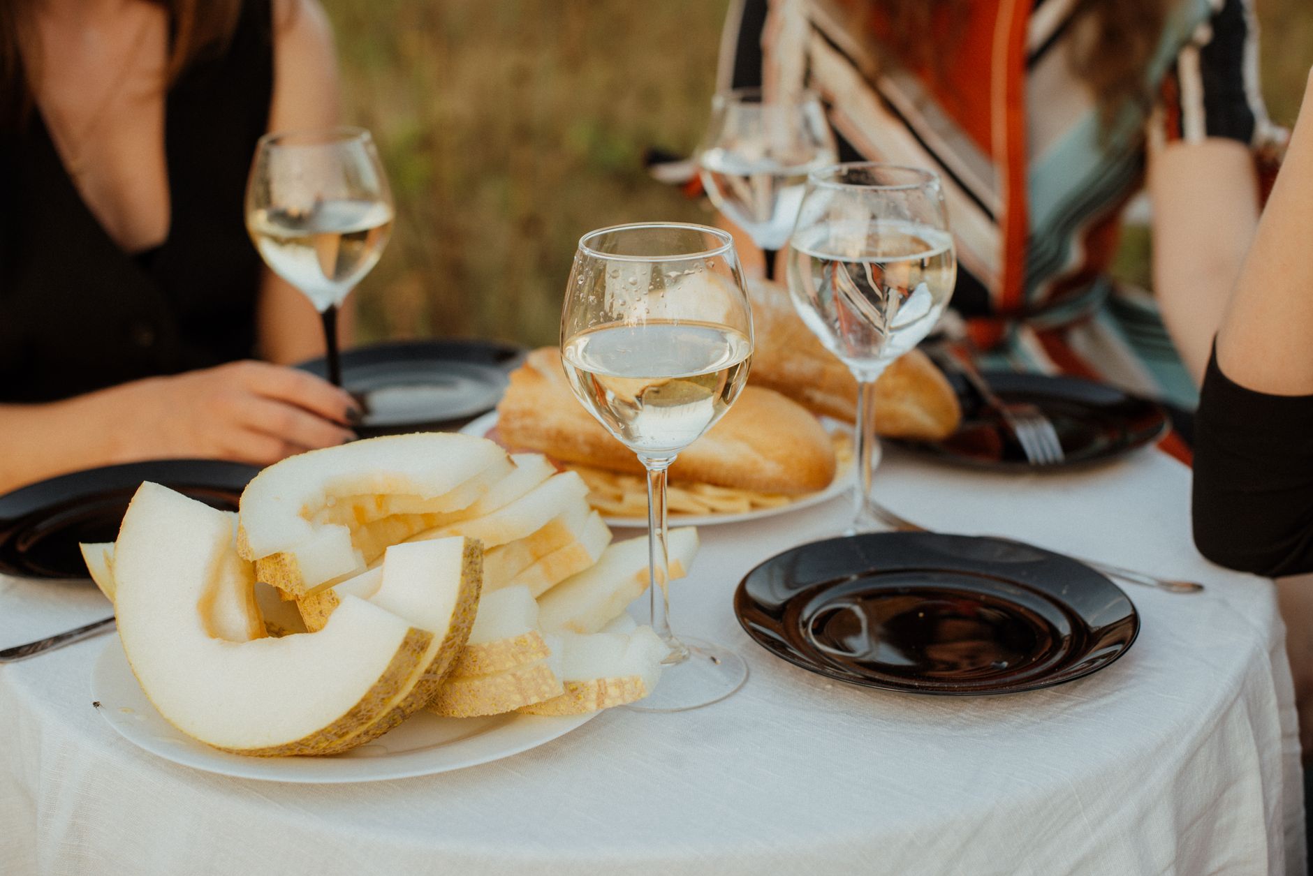 An outdoor table set with wine glasses and shared plates, the kind of meal where ritual still matters and the bottle keeps its place.