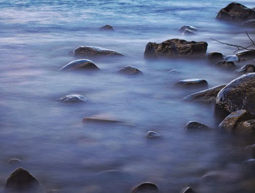 Free Serene long exposure photo capturing rocks in the ocean with calm water and soft lighting. Stock Photo