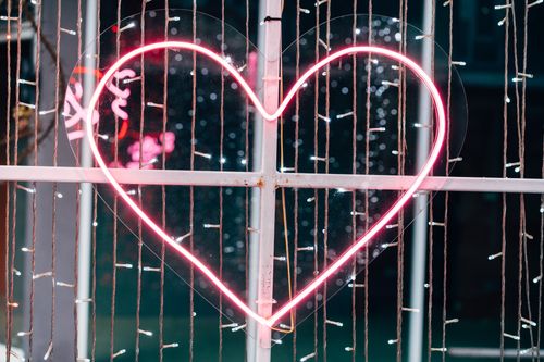 Free Neon pink heart light on a window with decorative string lights in Bangkok, Thailand, at night. Stock Photo