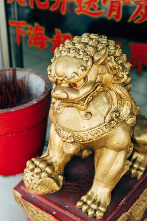Free Close-up of a golden lion statue in a Buddhist setting with red incense pot. Stock Photo