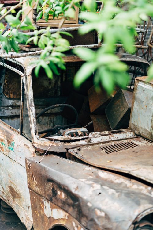 Free An abandoned rusty car surrounded by greenery signifies decay and nature reclaiming. Stock Photo