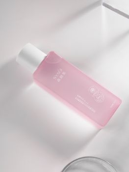 A pink skincare bottle with embossed details in a luxurious and minimalist setting.