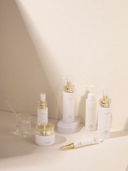 Minimalist cosmetics display featuring white and gold skincare bottles with soft lighting.