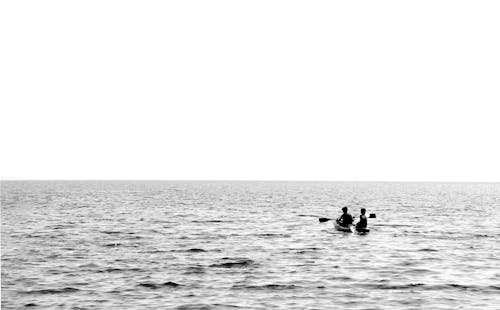 Grayscale Photo of People Riding a Boat in Water