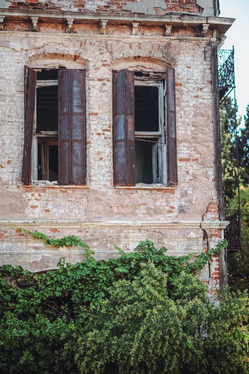 Free An old brick building with broken windows and lush green ivy, capturing deserted charm. Stock Photo