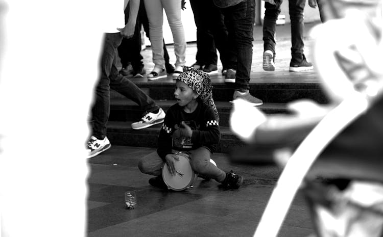 Girl On Ground Playing Drum Among People