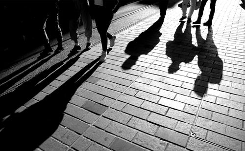 Free Dramatic black and white image of pedestrian shadows cast on a sidewalk. Stock Photo