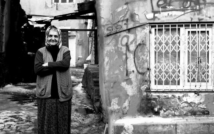 Old Woman In Handkerchief Near Old House