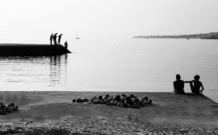 Silhouette Of People On The Concrete Dock Near Body Of Water