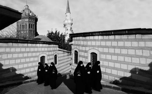 Black and White Photo of Muslim Women Walking up Narrow Street