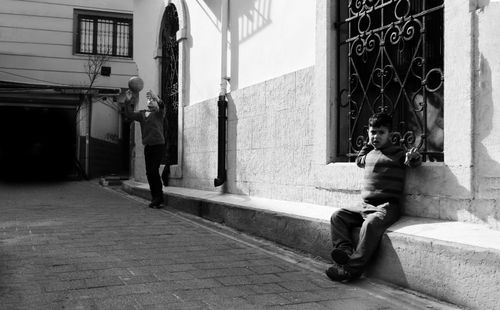 Free Two children playing basketball in a sunlit urban alley, black and white Stock Photo