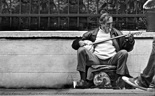 Man Playing a Stringed Instrument on the Sidewalk