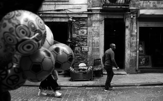 Black and white photo of people in an old town alley with balloons.
