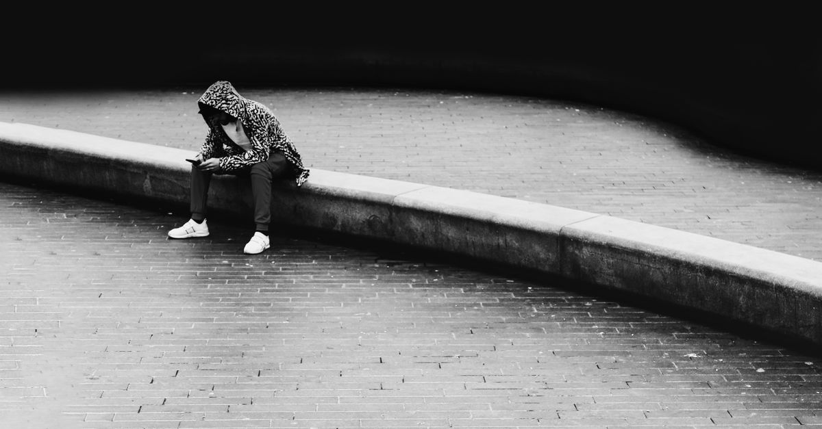 person sitting on a curb at sunset looking contemplative