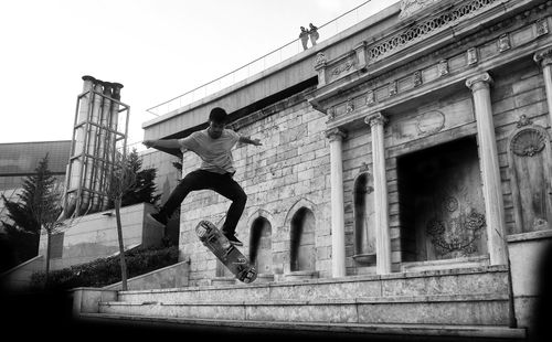Free Black and white image of a skateboarder performing a trick against an architectural backdrop. Stock Photo