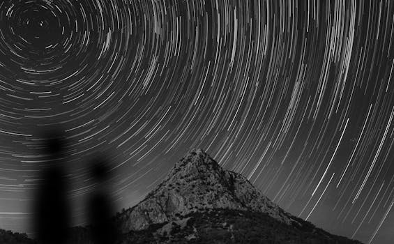Magnificent star trails create a mesmerizing spiral over a mountain landscape at night.