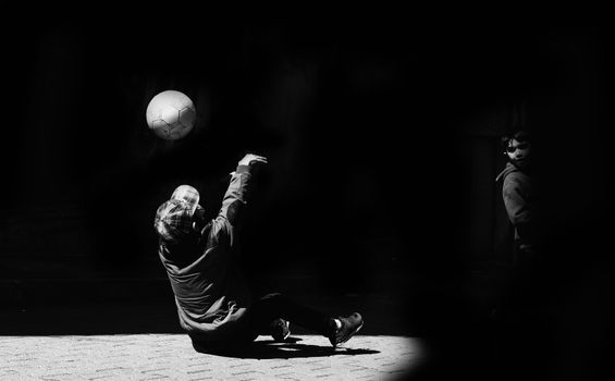 Black and white photo of kids playing with a soccer ball in an outdoor setting.