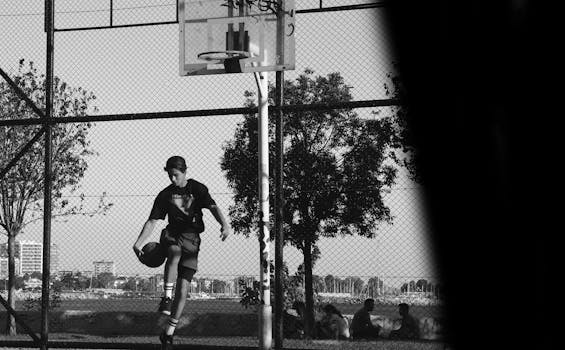 A young man playing basketball on an outdoor court in black and white.