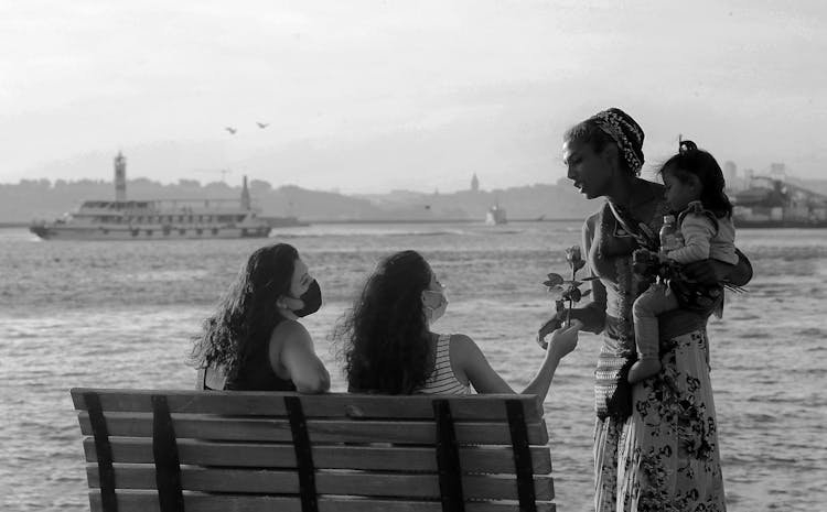 Woman Giving A Flower To Another Woman Holding A Baby 