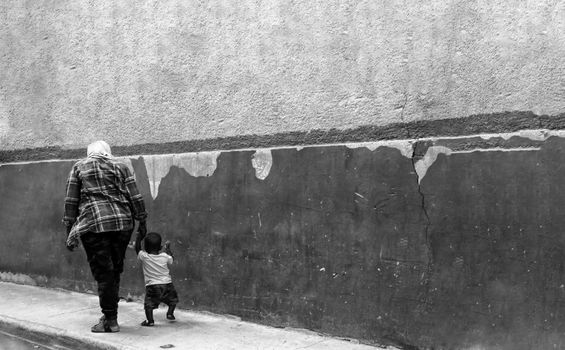 Grayscale Photo of Man Walking on Sidewalk