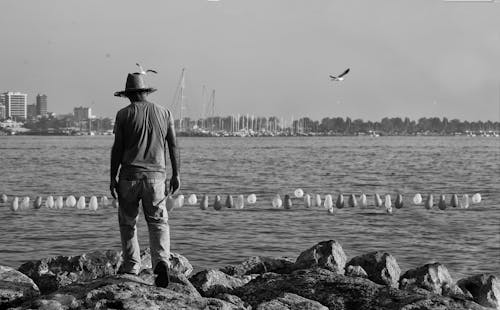 Man Walking on Rocks on Seashore