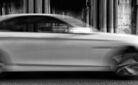 Monochrome panning shot capturing a car in motion with a blurred background, evoking speed and energy.