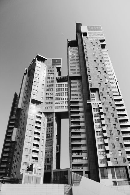 A stunning black and white photo showcasing a modern skyscraper with unique architecture in an urban setting.