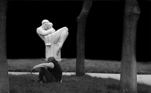 A Grayscale of a Man Sitting at a Park