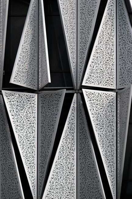 Close-up of contemporary geometric aluminum facade with textured tiles.